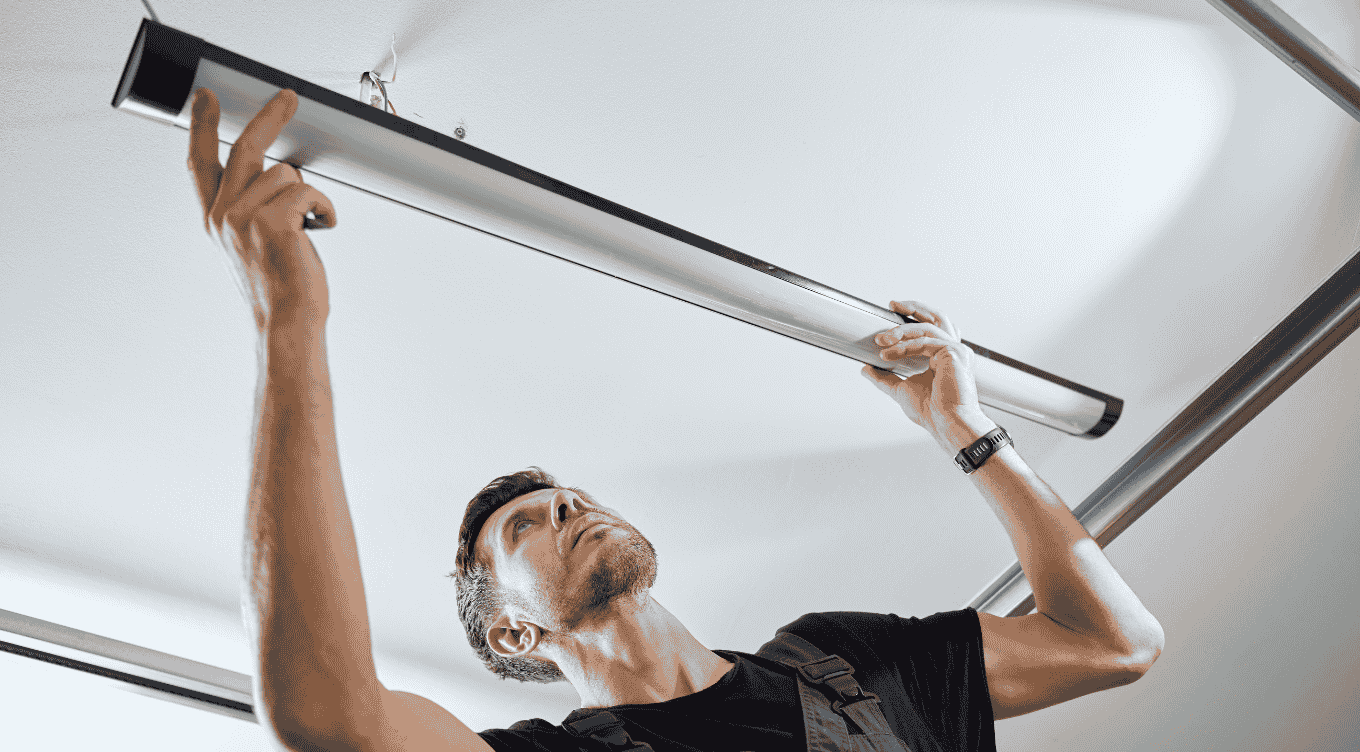 A technician carefully adjusts the uniyonds linear fixture to ensure optimal brightness in the workspace.